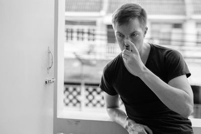 Portrait of young man using asthma pump at home