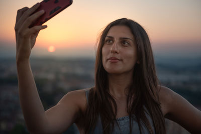 Portrait of young woman against sky during sunset