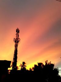 Low angle view of silhouette communications tower against sky during sunset