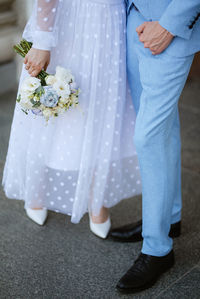 Low section of bride holding bouquet