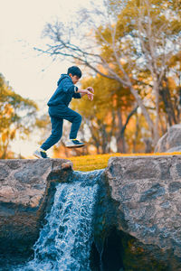 Child jumping over waterfall