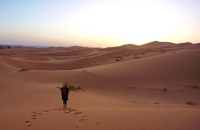 Woman standing in desert during sunset