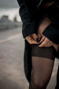 Midsection of woman holding umbrella standing on street