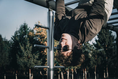 Young man hanging at jungle gym