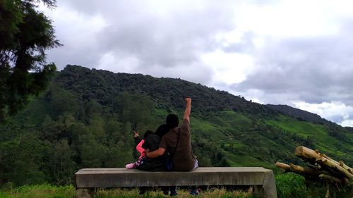 Rear view of men on mountain against sky