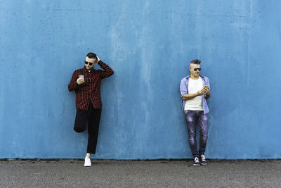 Full length portrait of young woman standing against wall