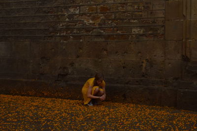 Woman sitting on brick wall