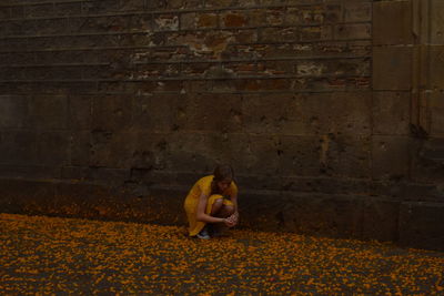 Woman sitting on brick wall