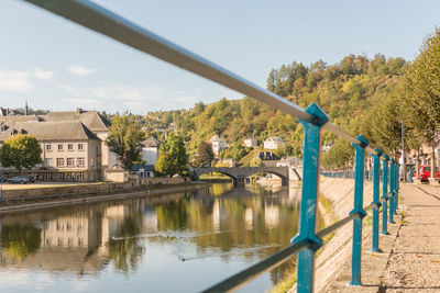 Bridge over river by buildings against sky