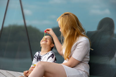 Happy blond woman and little boy sitting on terrace and eating sweets. mother and son