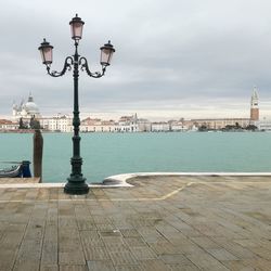 Street light by sea against sky