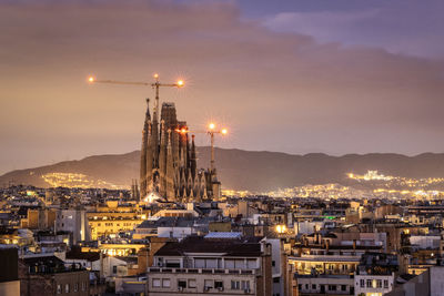 Illuminated cityscape of barcelona against sky at sunset