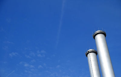 Low angle view of chimneys against blue sky