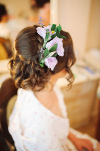 Bride wearing flowers on hair while sitting on chair