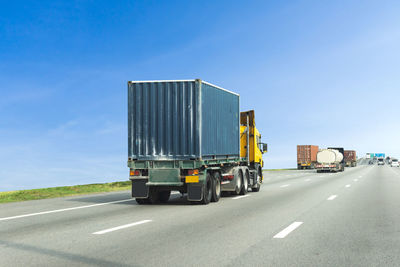 Vehicles on road against blue sky