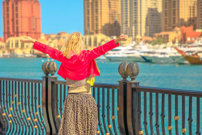 Woman standing against river and buildings in city