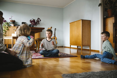 Siblings playing with ball in living room at home