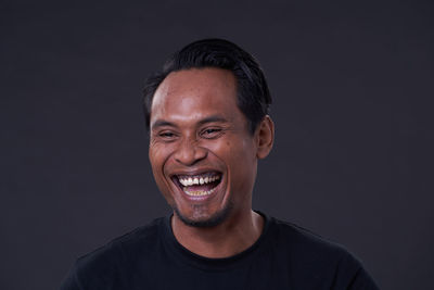 Portrait of smiling young man against black background