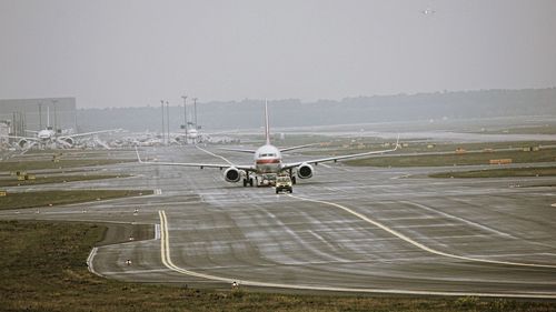 Airplane at airport runway against sky
