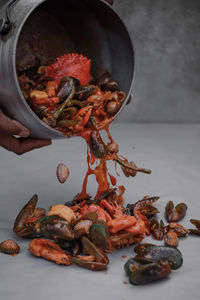 Close-up of human hand pouring seafood on table