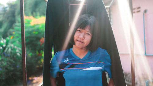 Portrait of smiling young woman standing against clothing