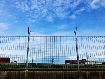 Low angle view of chainlink fence against blue sky