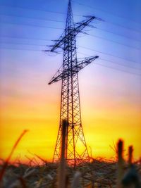 Low angle view of silhouette electricity pylon against sky during sunset