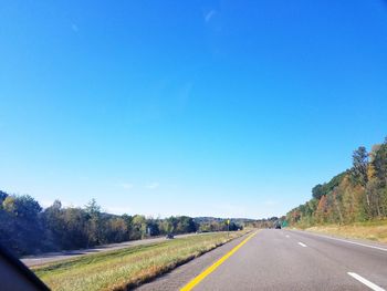 Empty road against clear blue sky