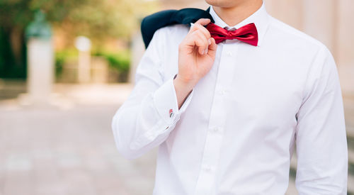 Midsection of woman holding white standing against blurred background