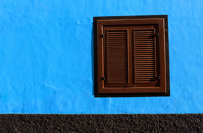 Close-up of closed window on blue wall