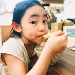 Close-up of young girl eating food at home