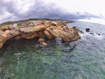 Rock formation in sea against sky