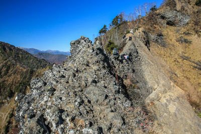 Low angle view of rocky mountains against clear blue sky