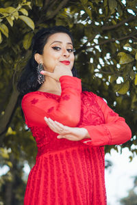 Beautiful young woman standing against red tree