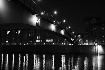 Illuminated bridge over river against sky at night