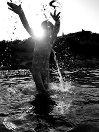 Silhouette man standing in water against sky