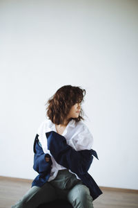 Portrait of girl sitting on the chair in motin against wall