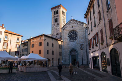 People on street amidst buildings against sky in city