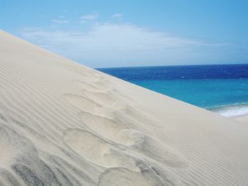 Sand dune at beach against sky at fuerteventura