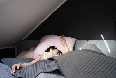 Low section of woman sitting on bed at home