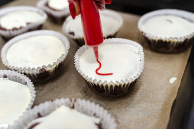 Chocolate-brown cupcakes wrapped in white paper and covered with white frosting with decorations.