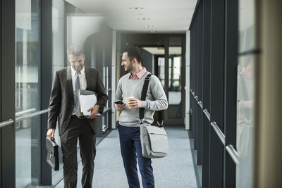 Two colleagues walking and talking on office floor