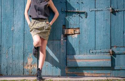 Low section of young woman standing against door