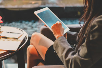 Midsection of businesswoman using digital tablet while sitting in office