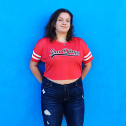 Portrait of young woman standing against blue background