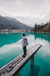 Rear view of woman standing at lake against sky