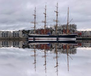 Sailboats moored at harbor against sky