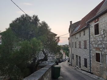 Road amidst trees and buildings against sky