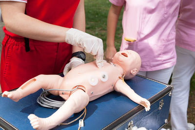 Midsection of paramedics practicing on cpr dummy