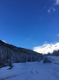 Scenic view of snow mountains against blue sky